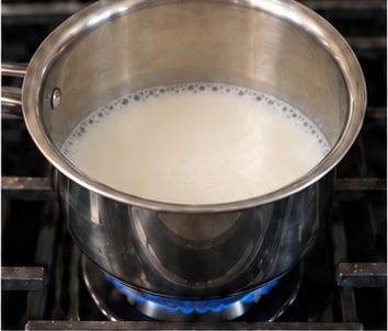 Milk coming to a boil in a small pan on the stove